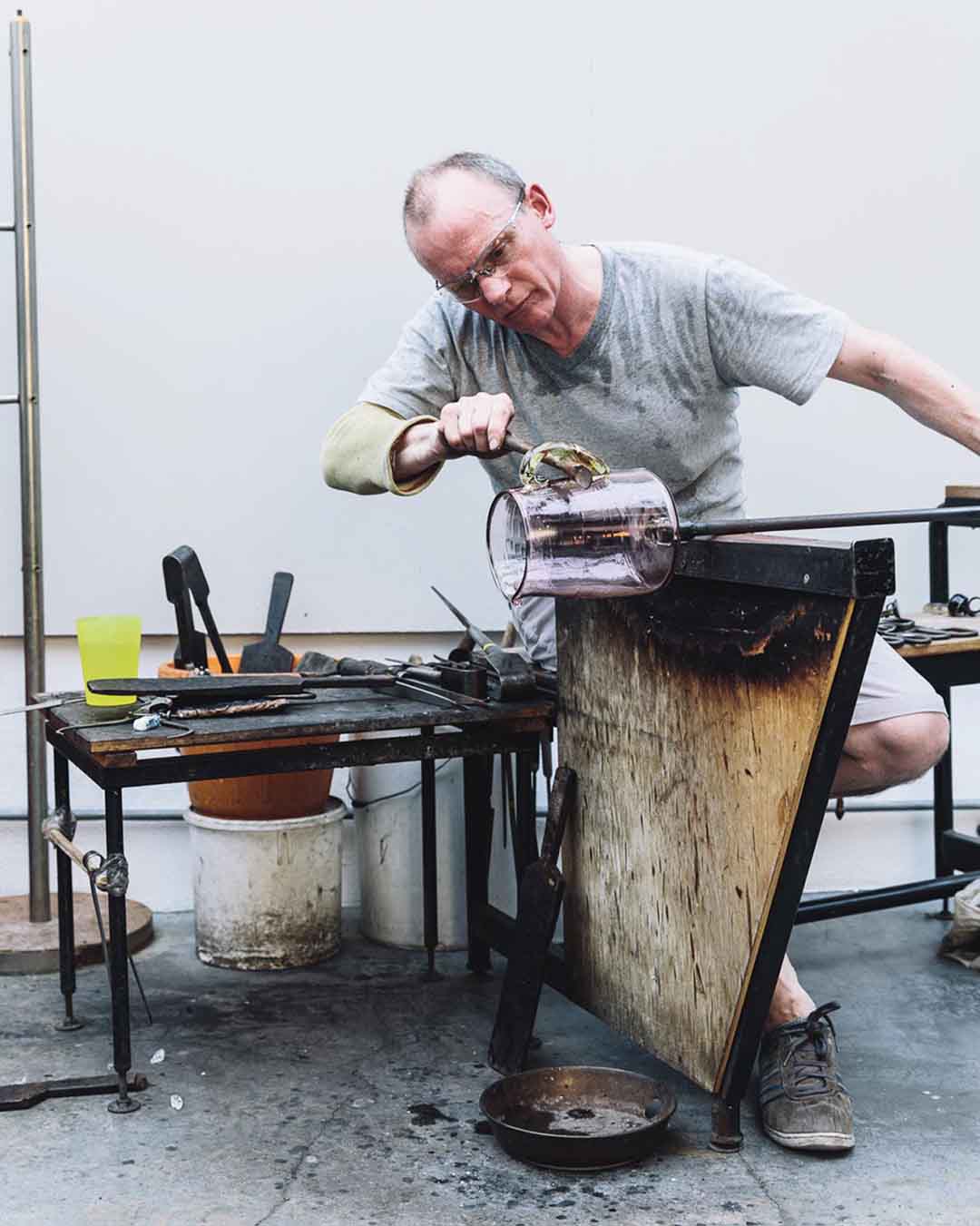 blown glass maker in his glass workshop making a glass jug