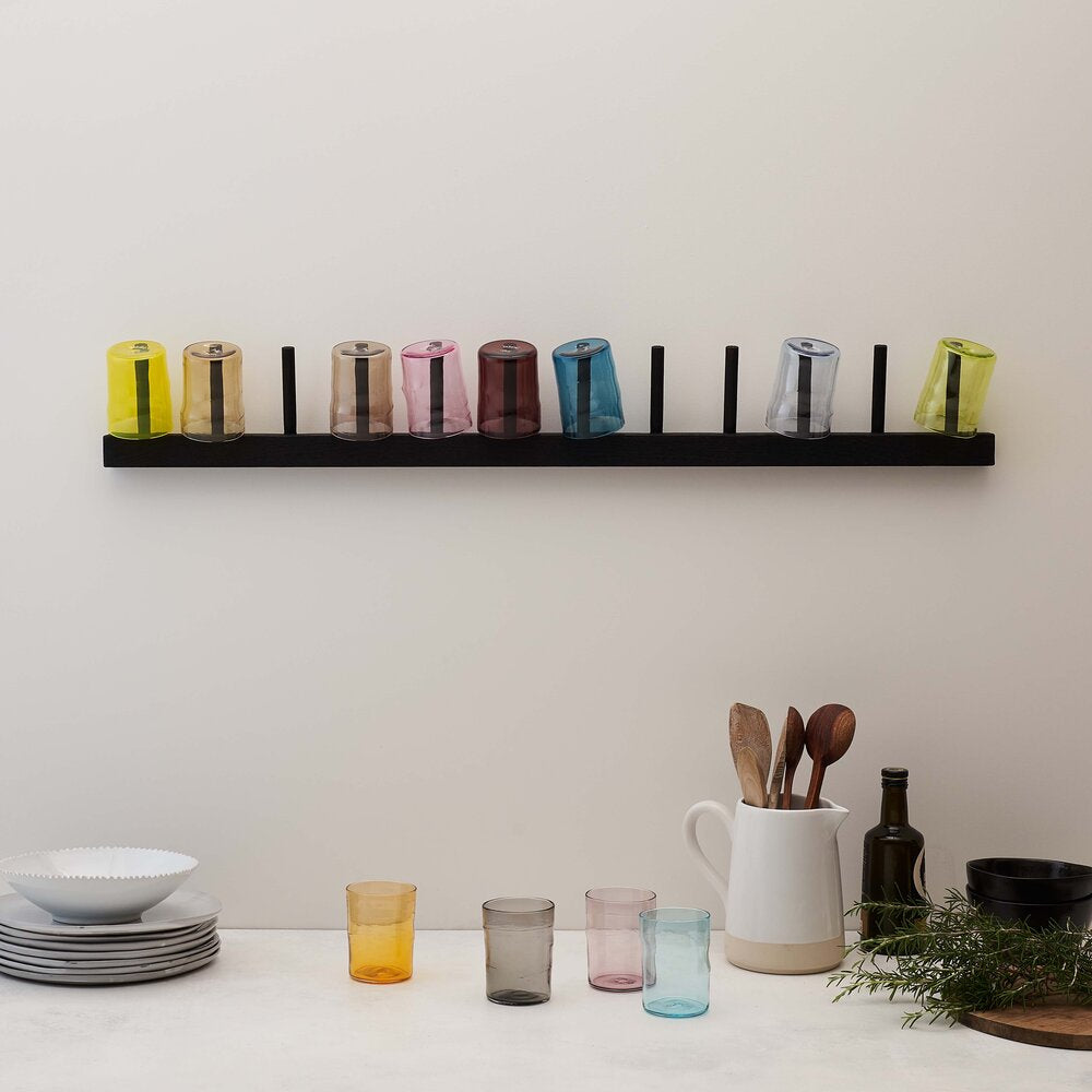 12 coloured glass tumblers on a wall mounted rack